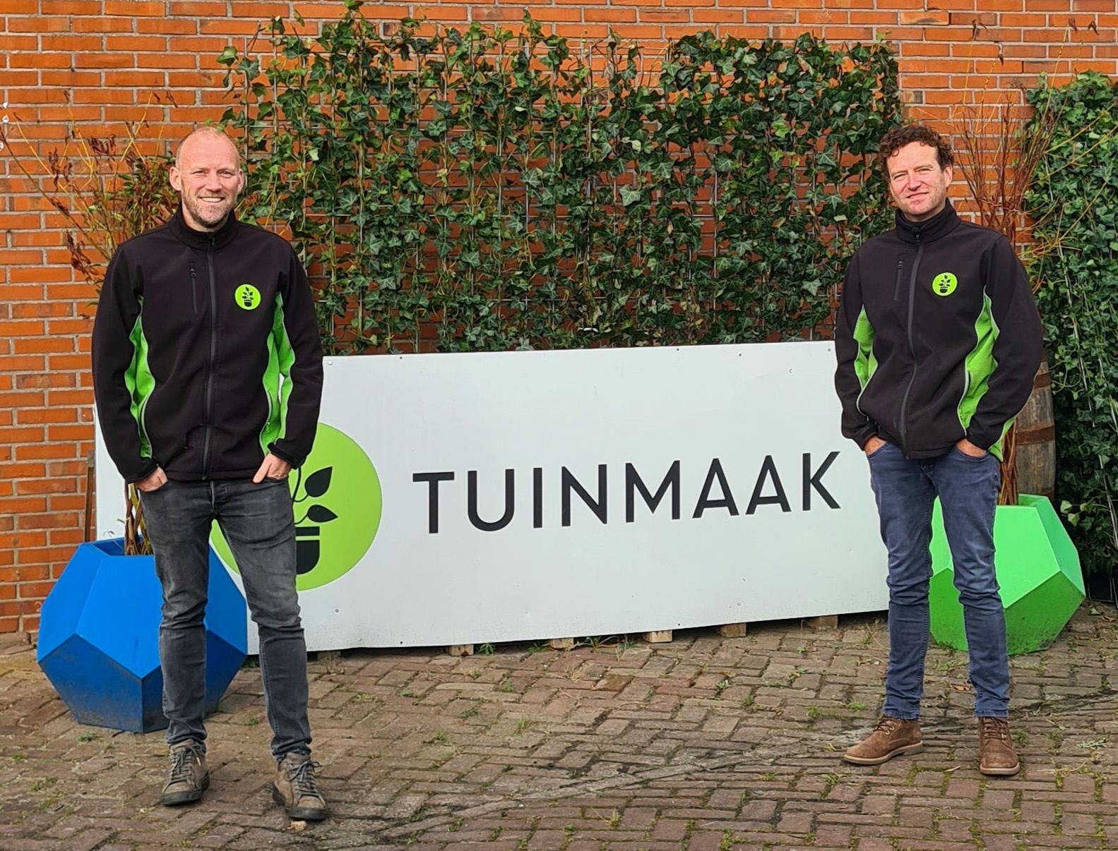 Oprichters van Tuinmaak bij hun logo