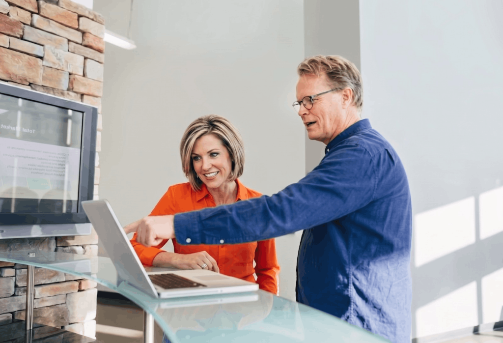 Twee professionals werken samen achter een laptop.