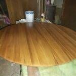 Masă rotundă din lemn cu un finisaj neted, așezată pe o suprafață de lucru.